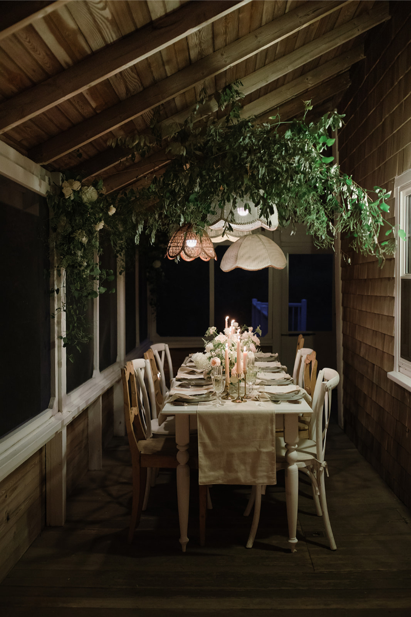 Floral hanging garden with light fixtures of table seating. 