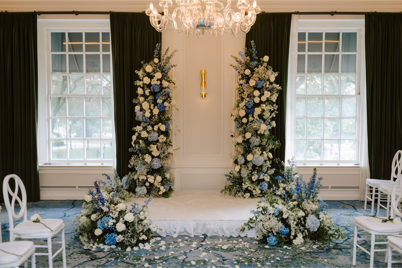 Untraditional wedding arch made of blue and white floral pillars. 