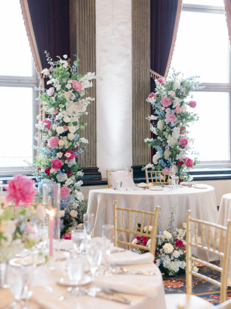 Wedding decor of two floral column installments using pink, blue, and white seasonal flowers and greenery. 