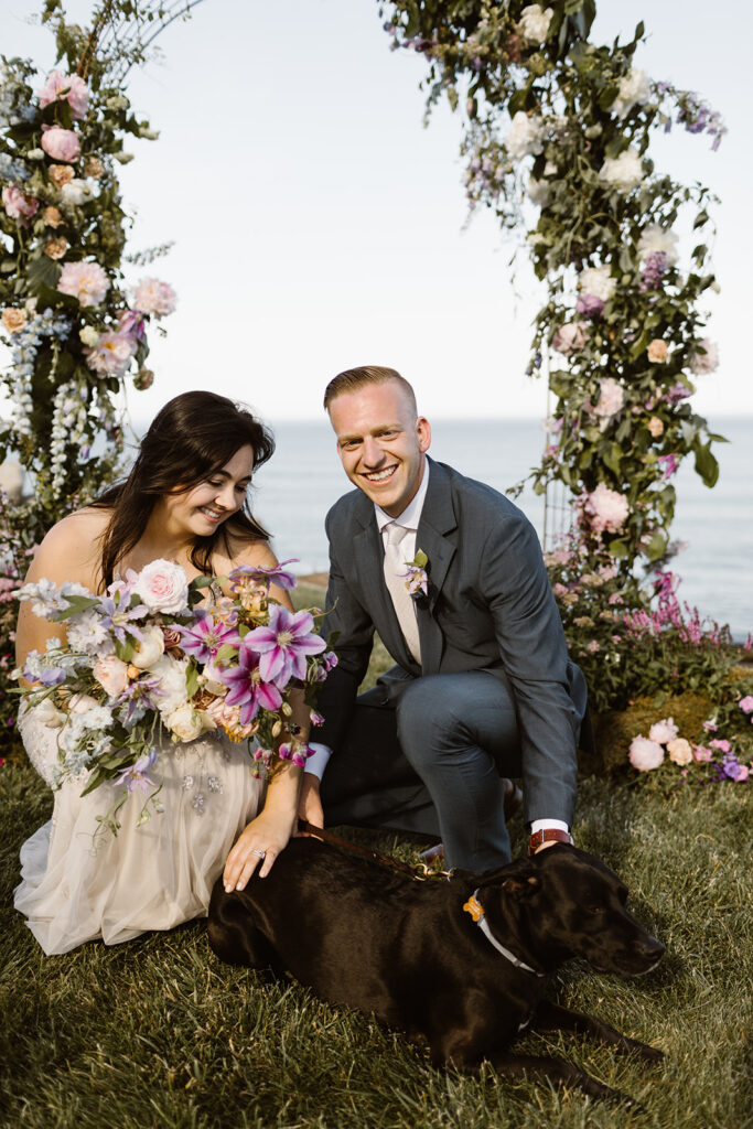 bride and groom petting do with gorgeous ceremony florals in background