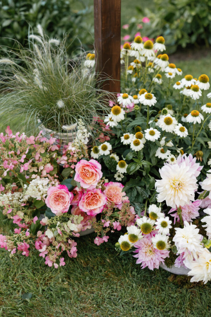 Close up of summer flower arrangement at base of wedding arch. 