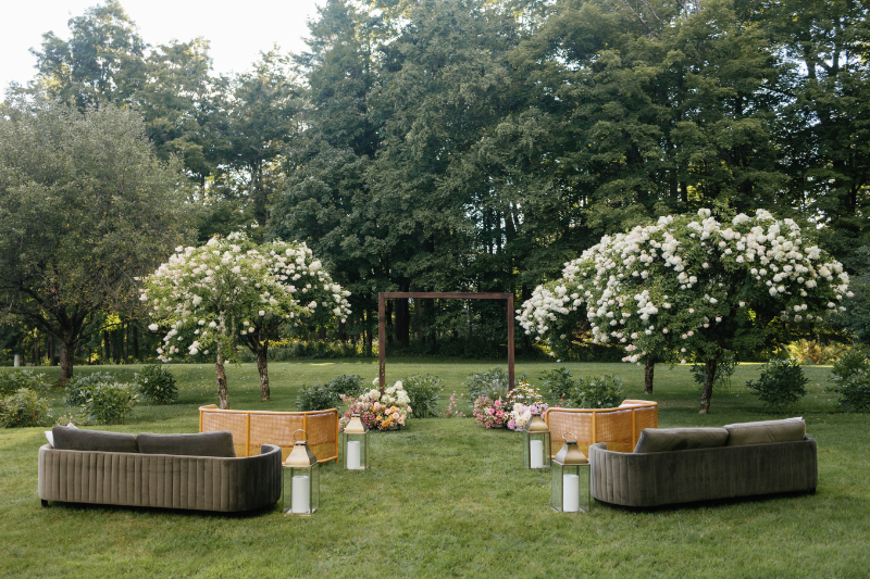 Wedding ceremony layout with lounge furniture, lanterns, and seasonal flower arrangements. 