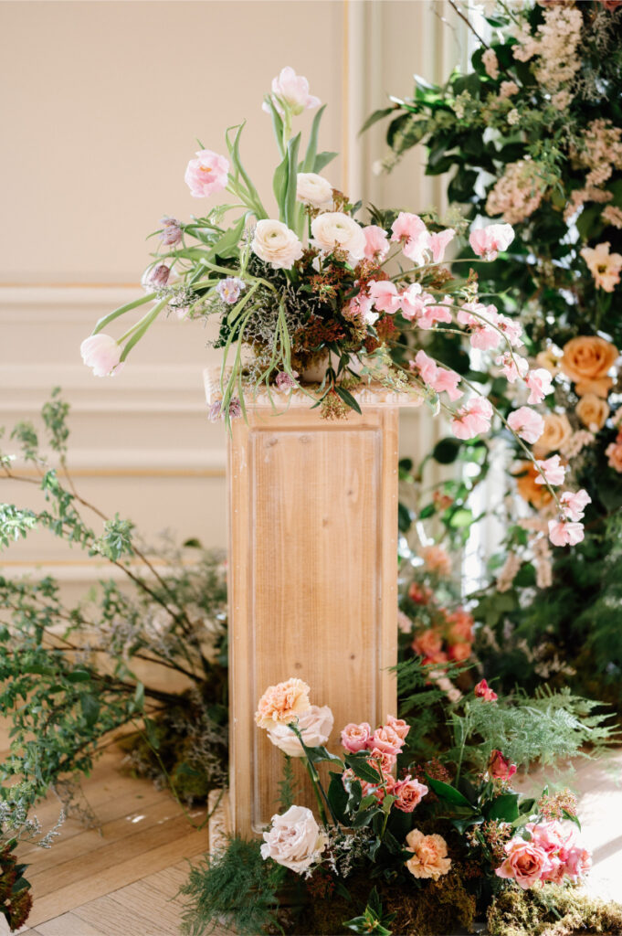 2025 wedding floral trend of flower sculpture using range of pink florals sitting on wooden pedestal. 