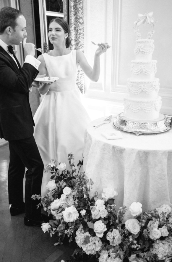 black and white shot of cake garden and couple tasting their 4 tier wedding cake