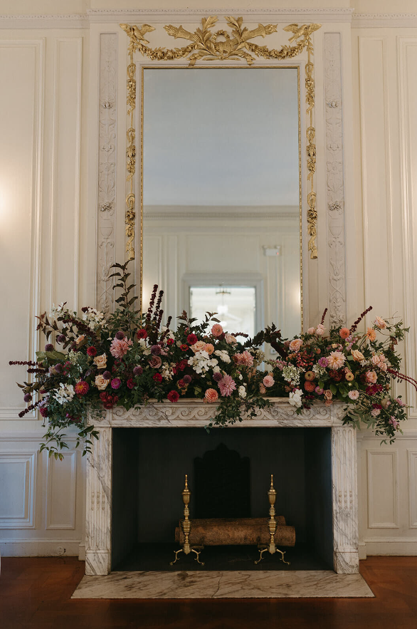 fireplace decorated with floral runner of burgundy, blush, white and greenery