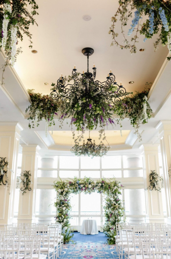 floral arch of white blooms and greenery and hanging arrangements of the same color