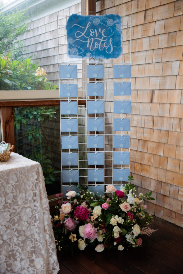 A love notes display paired with lush pink, white, and magenta floral arrangements on a wooden deck.