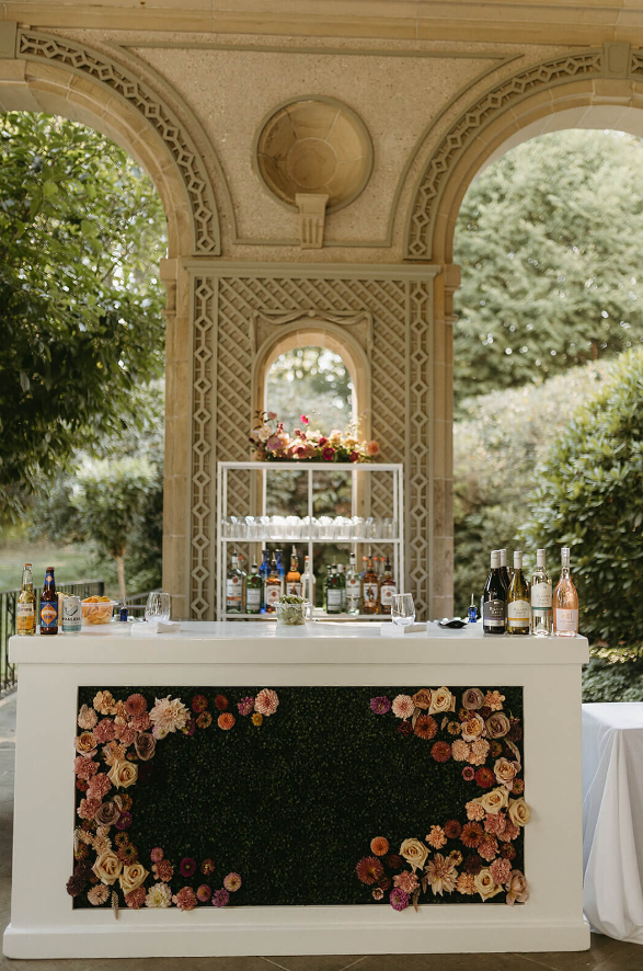 A chic bar setup featuring a lush floral base with blush, ivory, and pink blooms