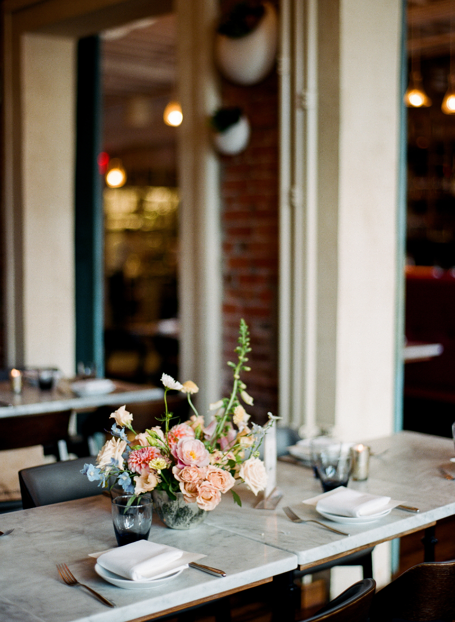 Dining table with a marble surface, floral centerpiece, white napkins, and glasses, set for a formal occasion