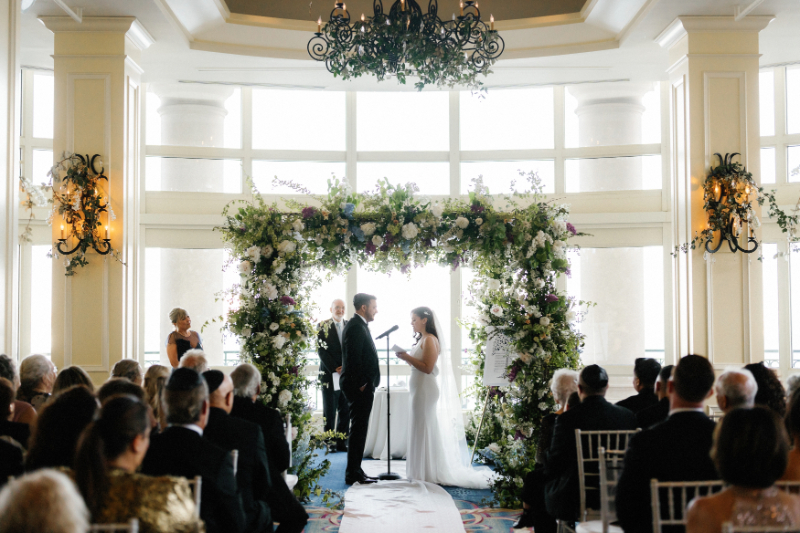 Couple exchanging vows under the chuppah at the Boston Harbor Hotel 