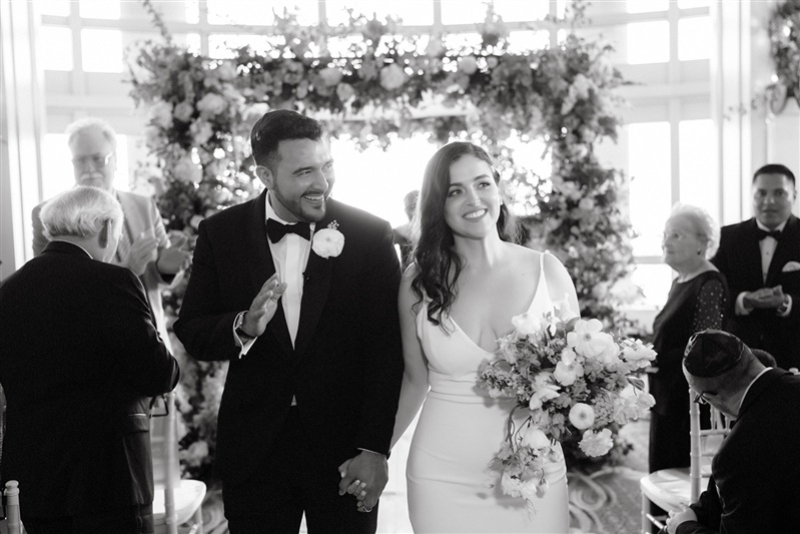 candid black and white photo of the bride and groom walking down the isle officially married 