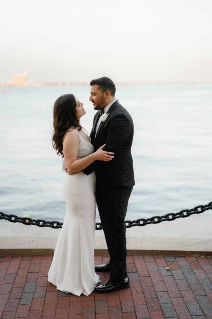 Couple embracing by the harbor on their wedding day 