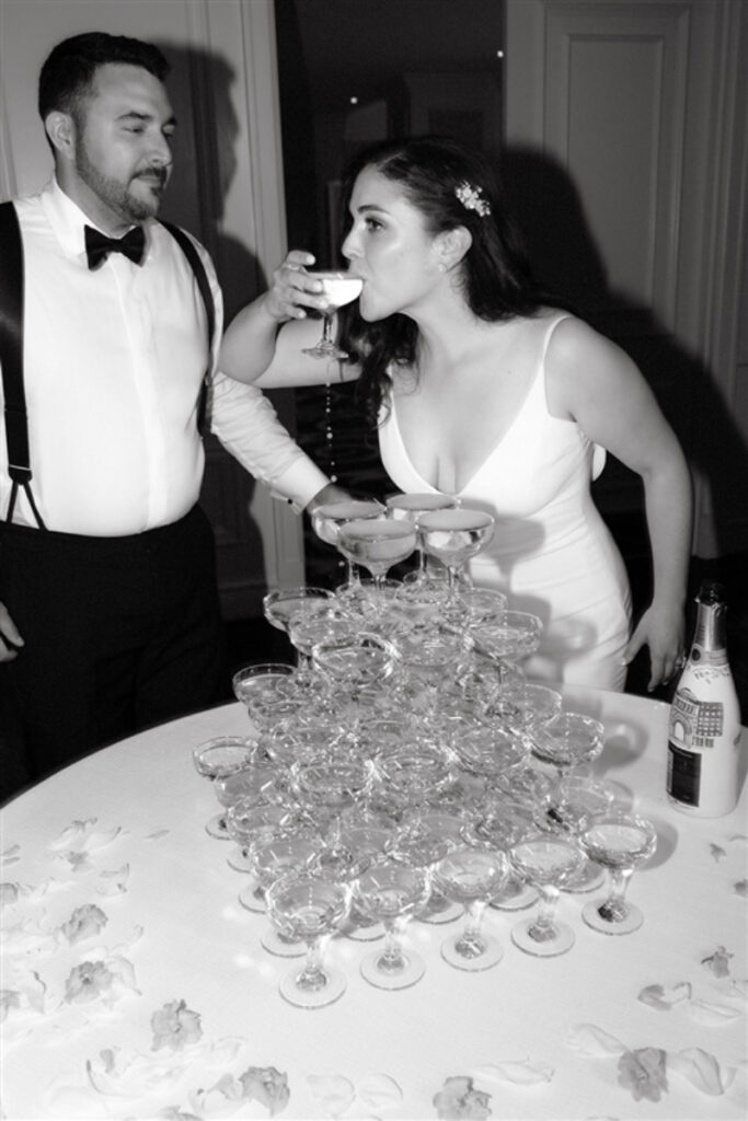 black and white photo of bride sipping champagne from the champagne tower