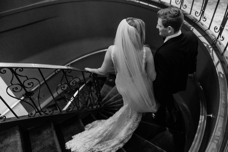 couple in black and white walking down a stunning staircase at the Newbury Boston