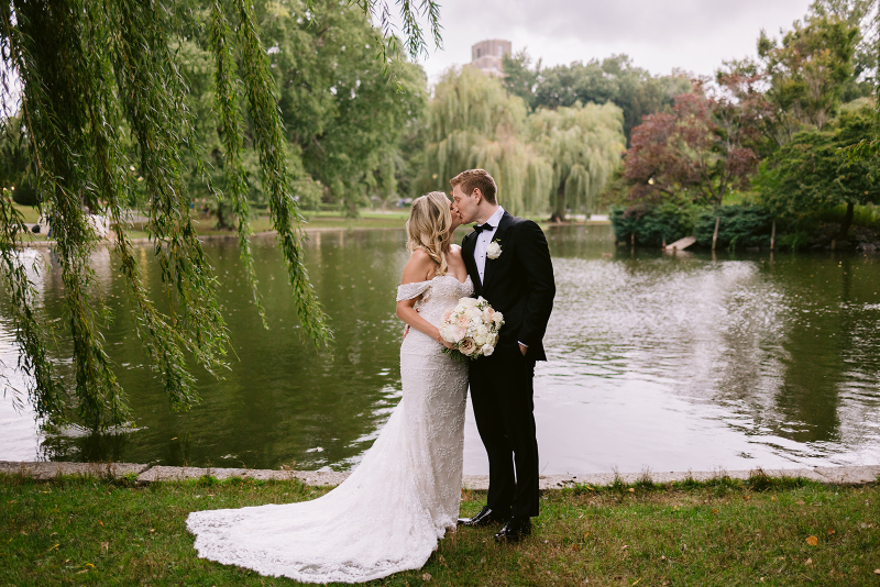 bride and groom kissing by the pond on their wedding day 