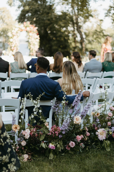 guests waiting for the wedding to start, sitting along the floral lined aisle