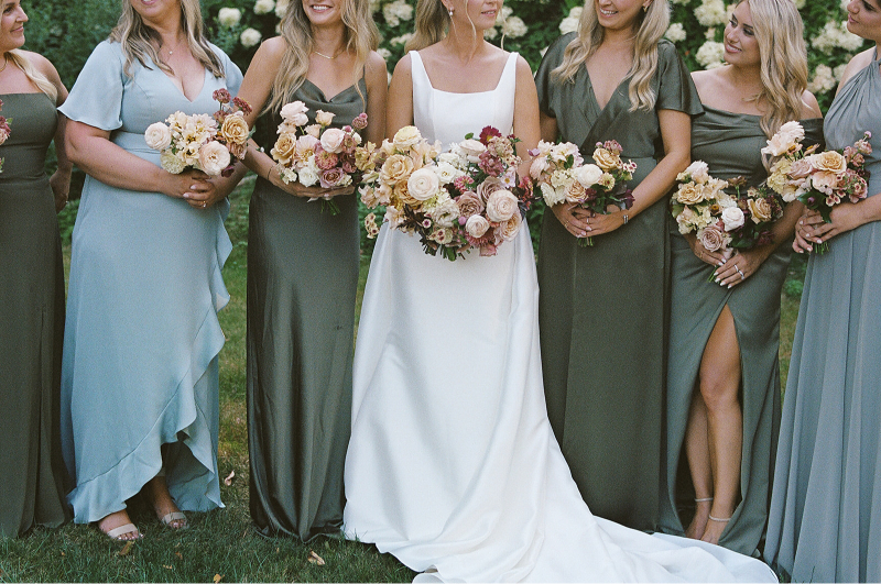 bridge standing with her bridesmaids holding their bouquets 